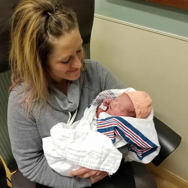 Smiling mother holding newborn baby.